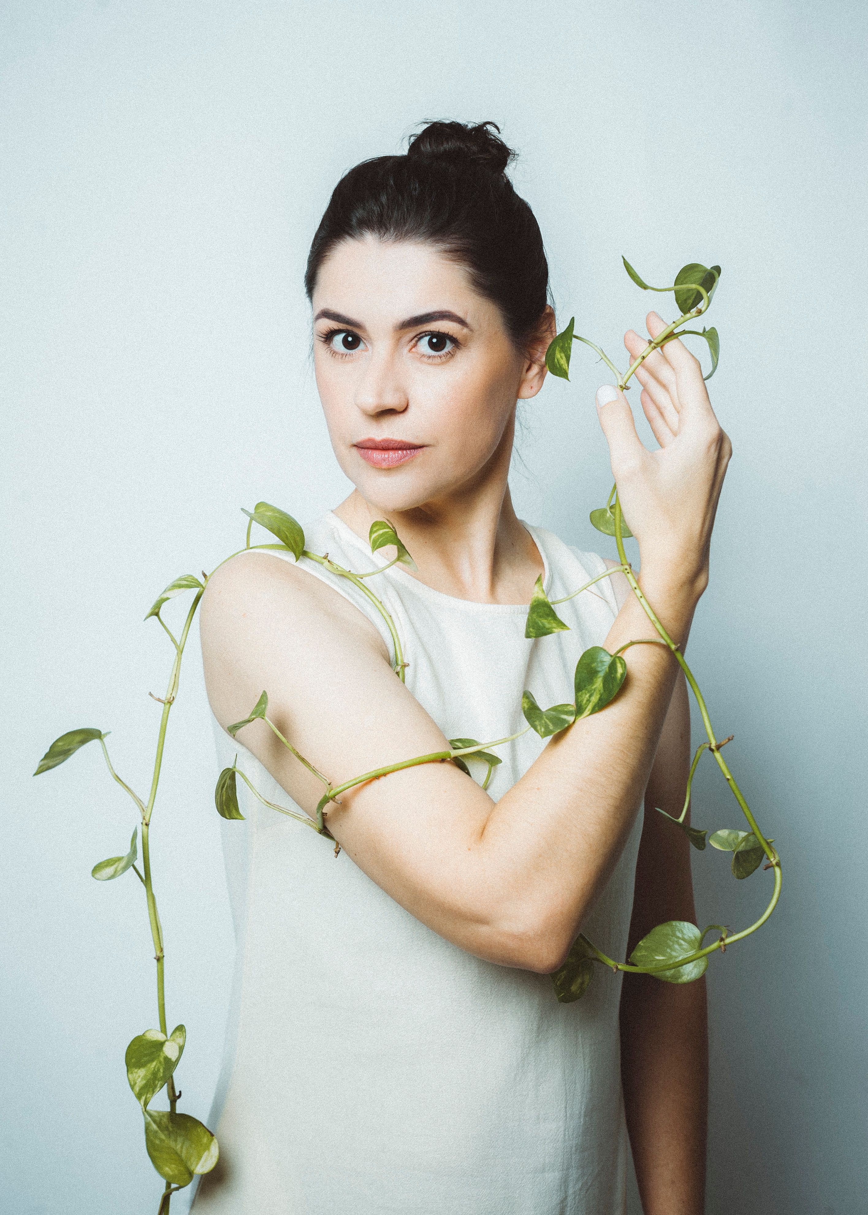 Woman with plant vines elegantly wrapped around, creating a modern natural aesthetic.