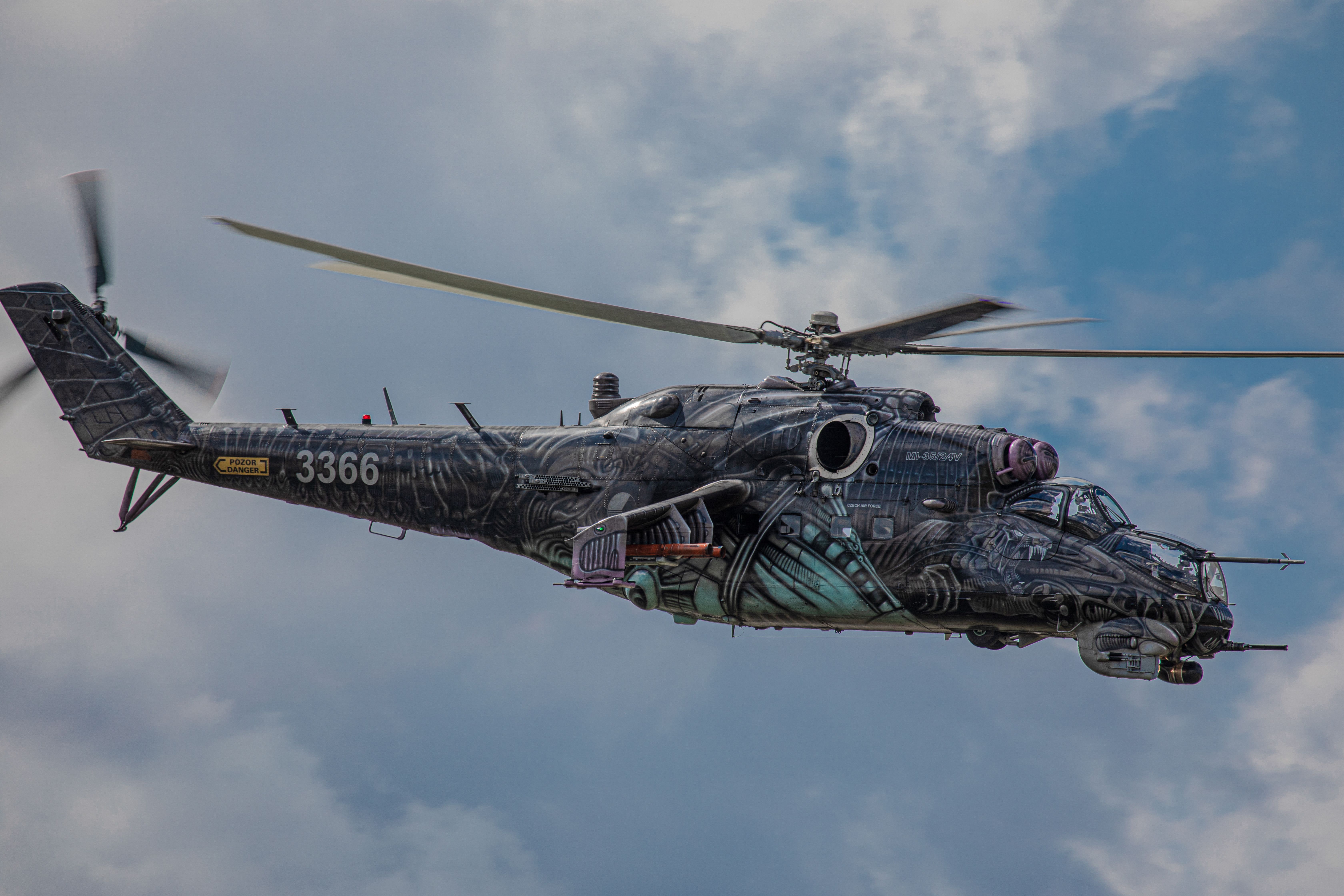 A visually striking Mi-24 helicopter soaring through a clear sky in Slovakia, showcasing a unique artistic paint job.