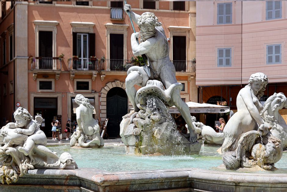 Person refilling a water bottle at a traditional Nasoni public drinking fountain in Rome