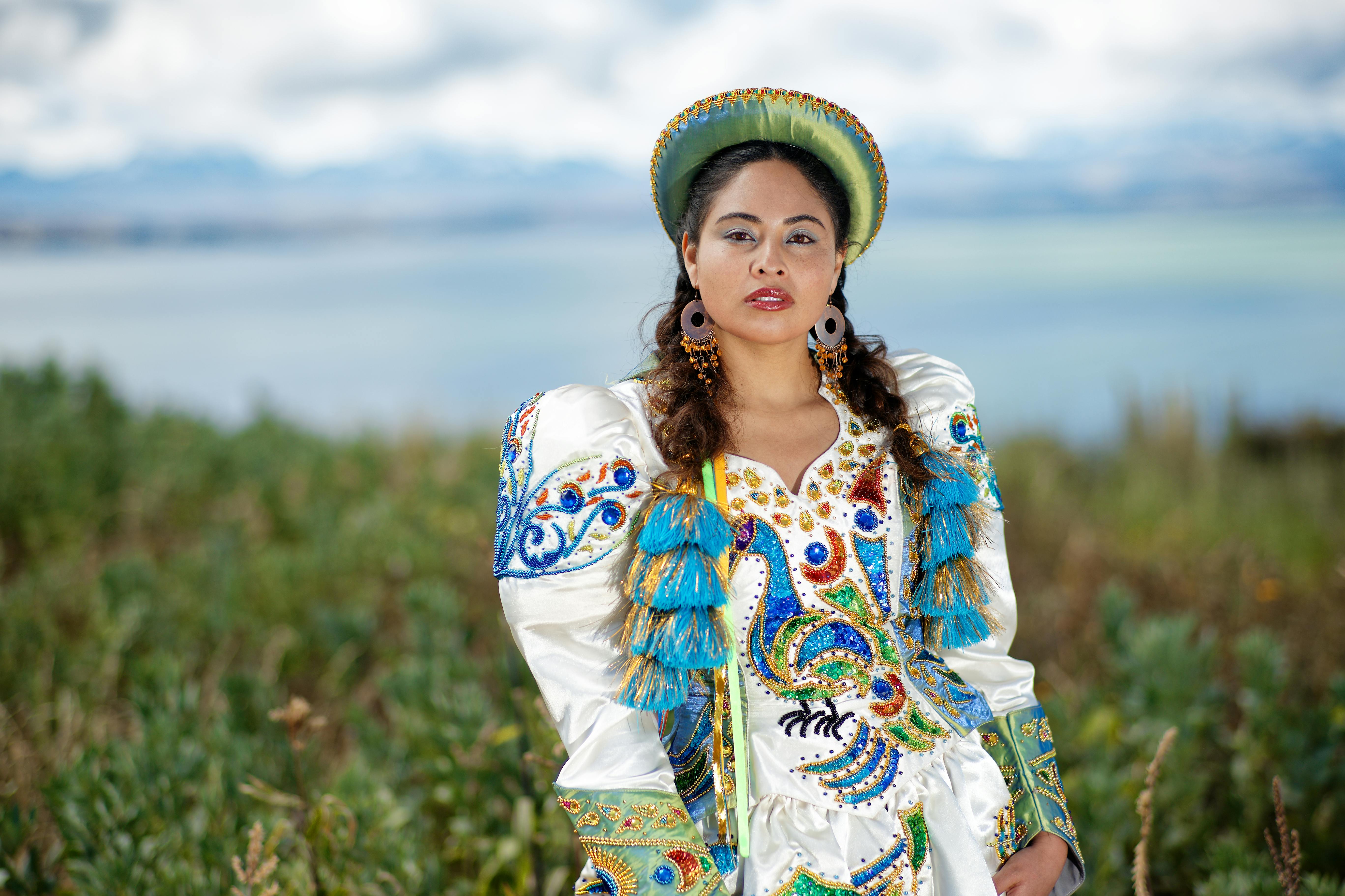 a woman in a colorful costume standing in front of the ocean