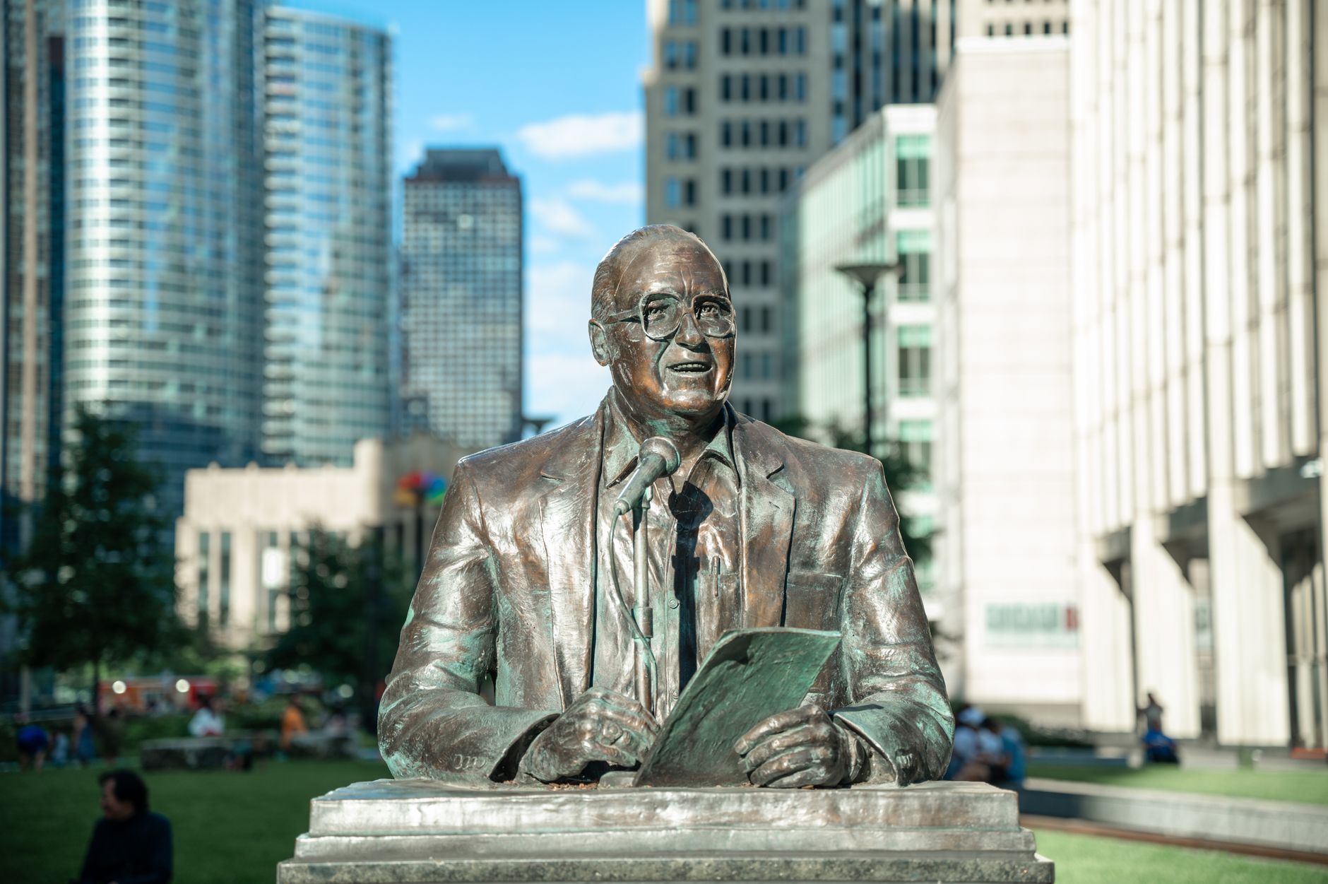Bronze statue of a man with skyscrapers in a bustling cityscape. Captures urban culture and architectural design.