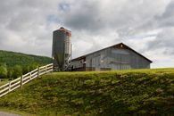 Brown and Gray Wooden House on Green Grass Field Under Gray Cloudy Sky