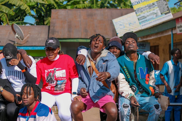 A Group Of Young Men Sitting Outside 