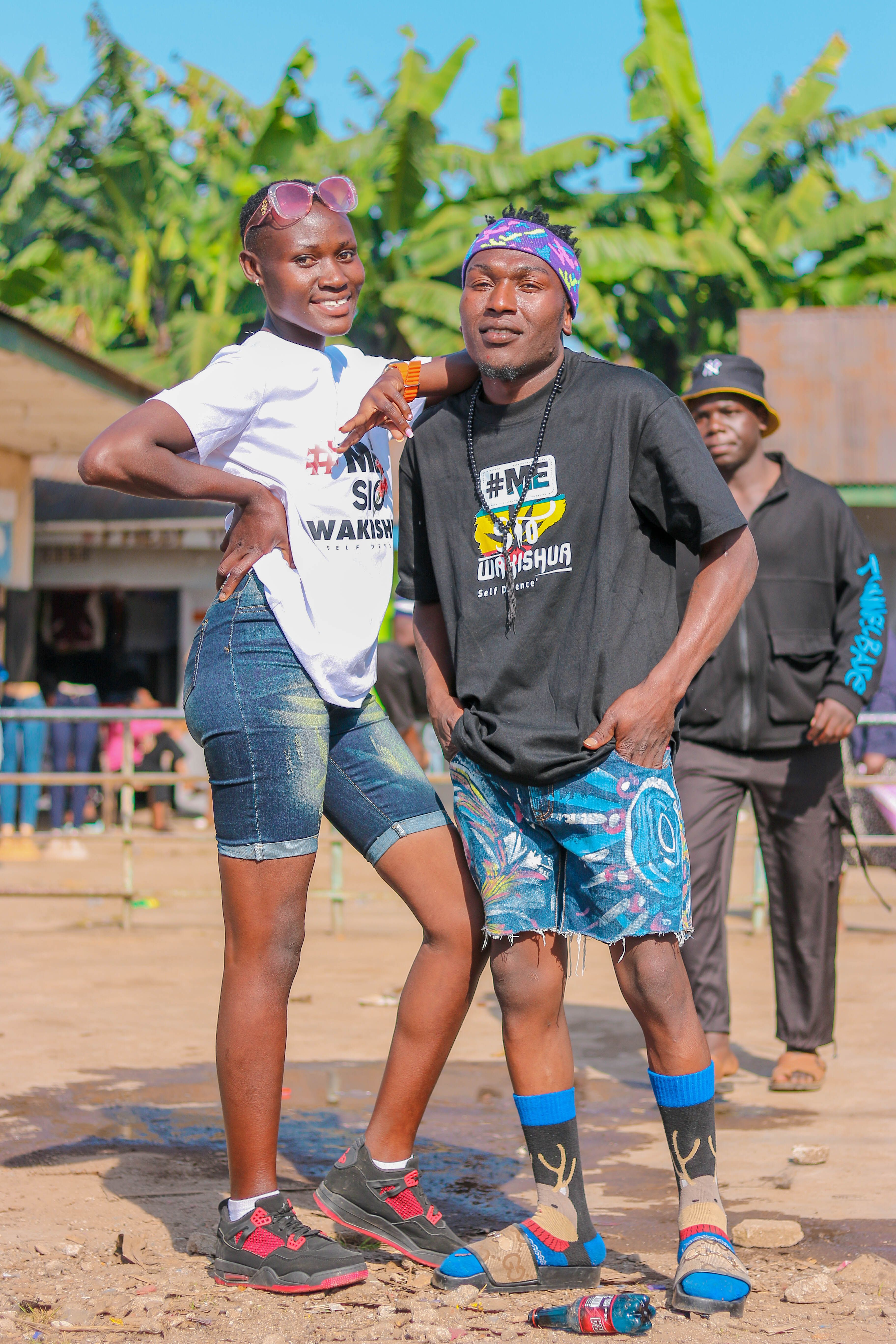 A cheerful couple smiling and posing outdoors during the day, exuding happiness and energy.