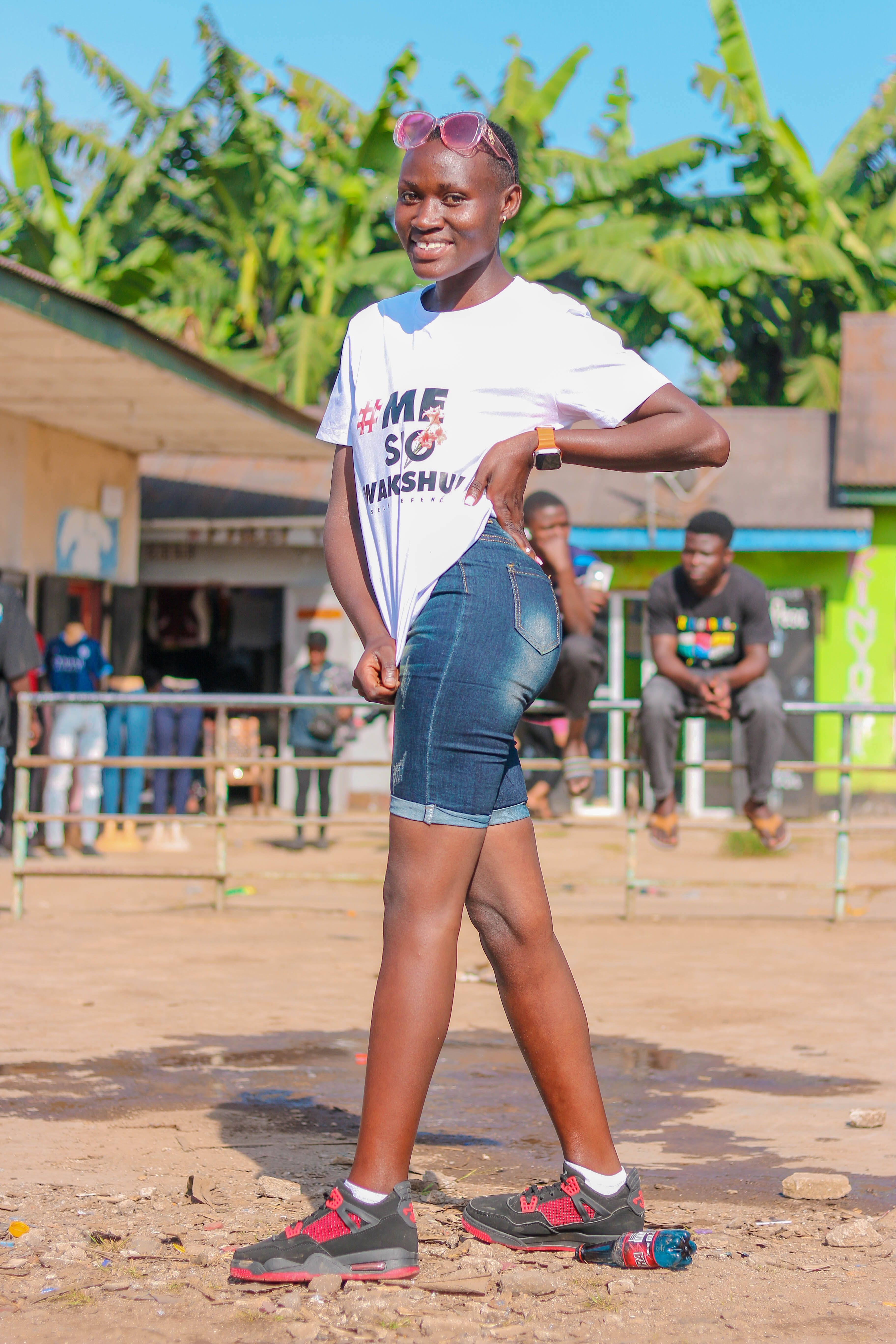 Confident young woman posing in casual attire outdoors on a sunny day.