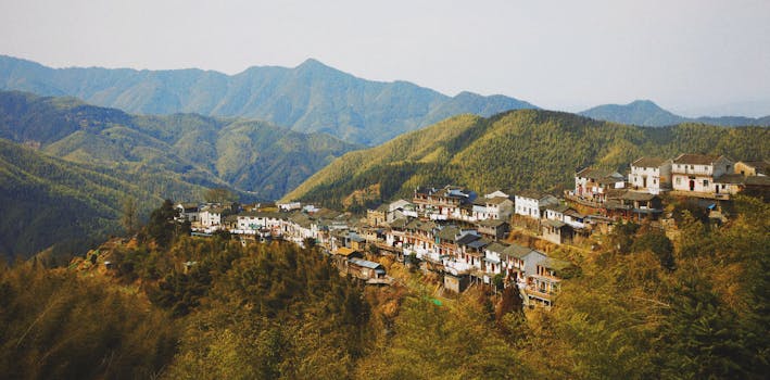 Beautiful aerial view of a village nestled in lush green mountains with scenic surroundings.