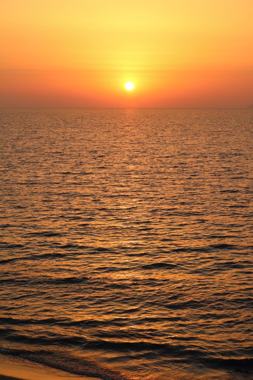 Free A serene sunrise view over the tranquil ocean, with golden hues reflecting on the water. Stock Photo