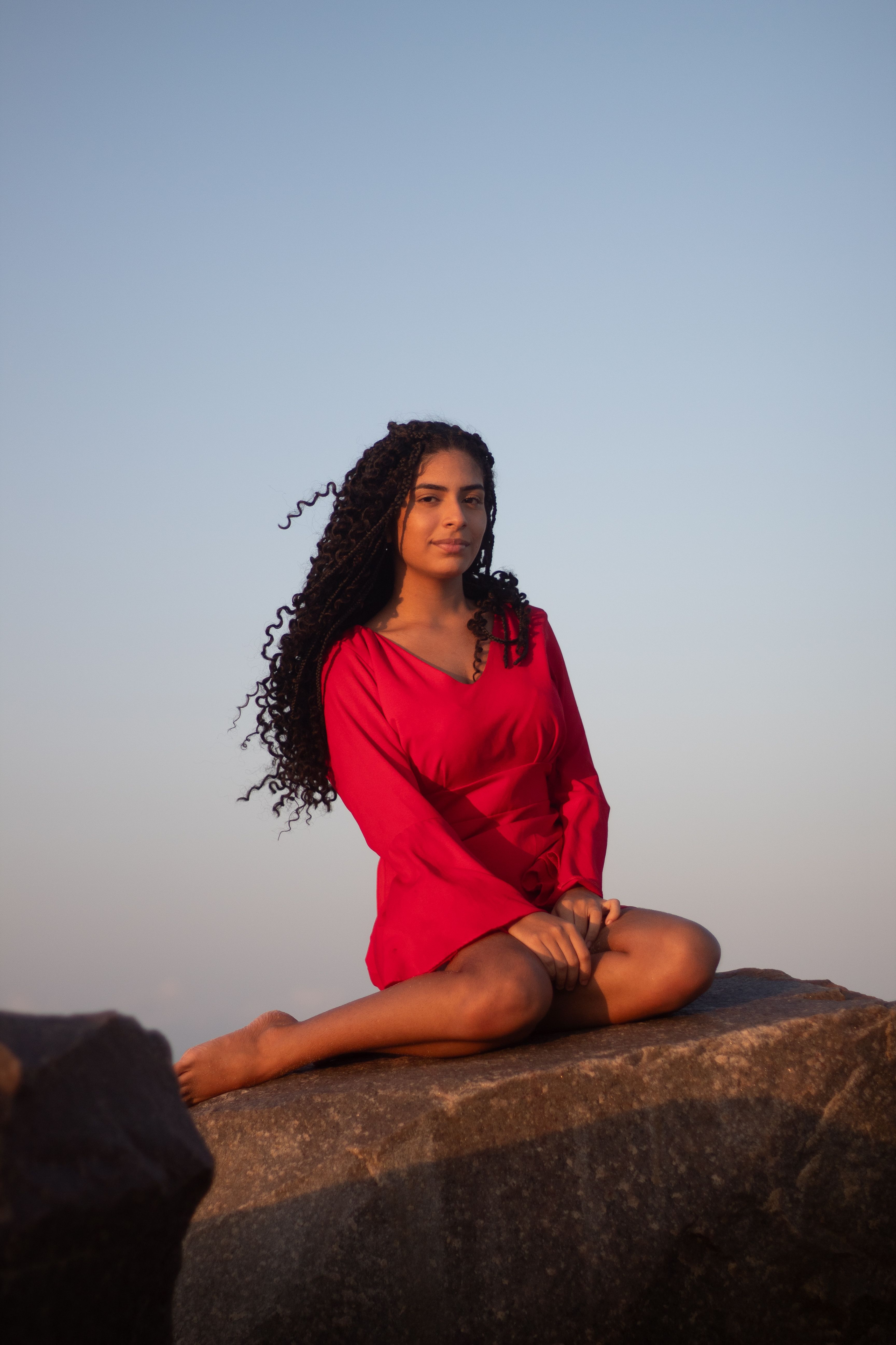 A woman sitting on a rock in a red dress · Free Stock Photo