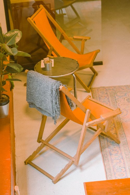 Free A stylish indoor café setting with vibrant orange folding chairs and cozy decor. Stock Photo