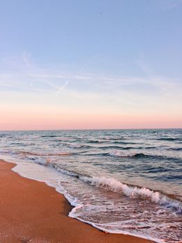 A tranquil beach setting with gentle ocean waves under a pastel sunset sky.