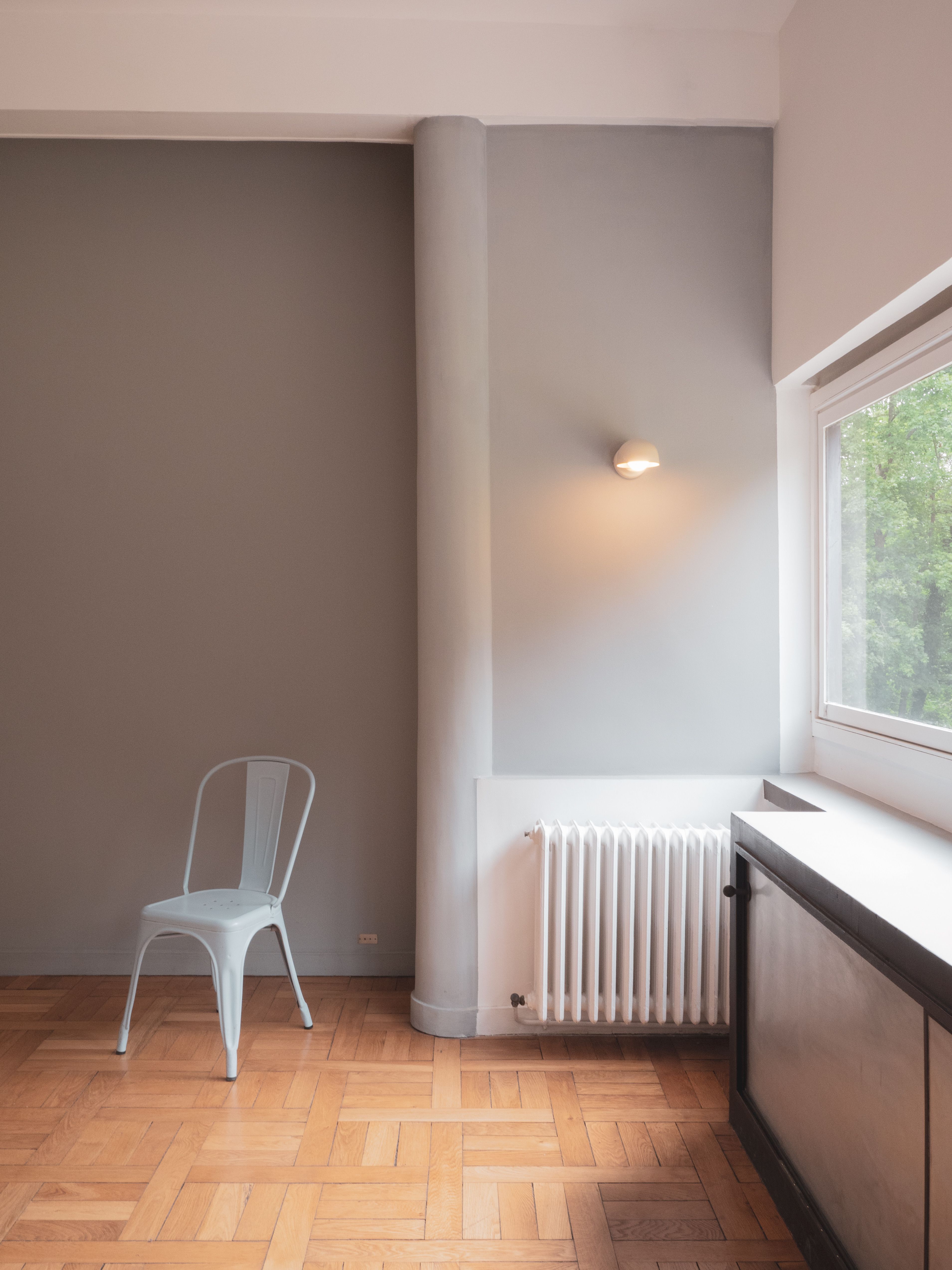 Simple and elegant interior design featuring a chair and large window in a Paris apartment.
