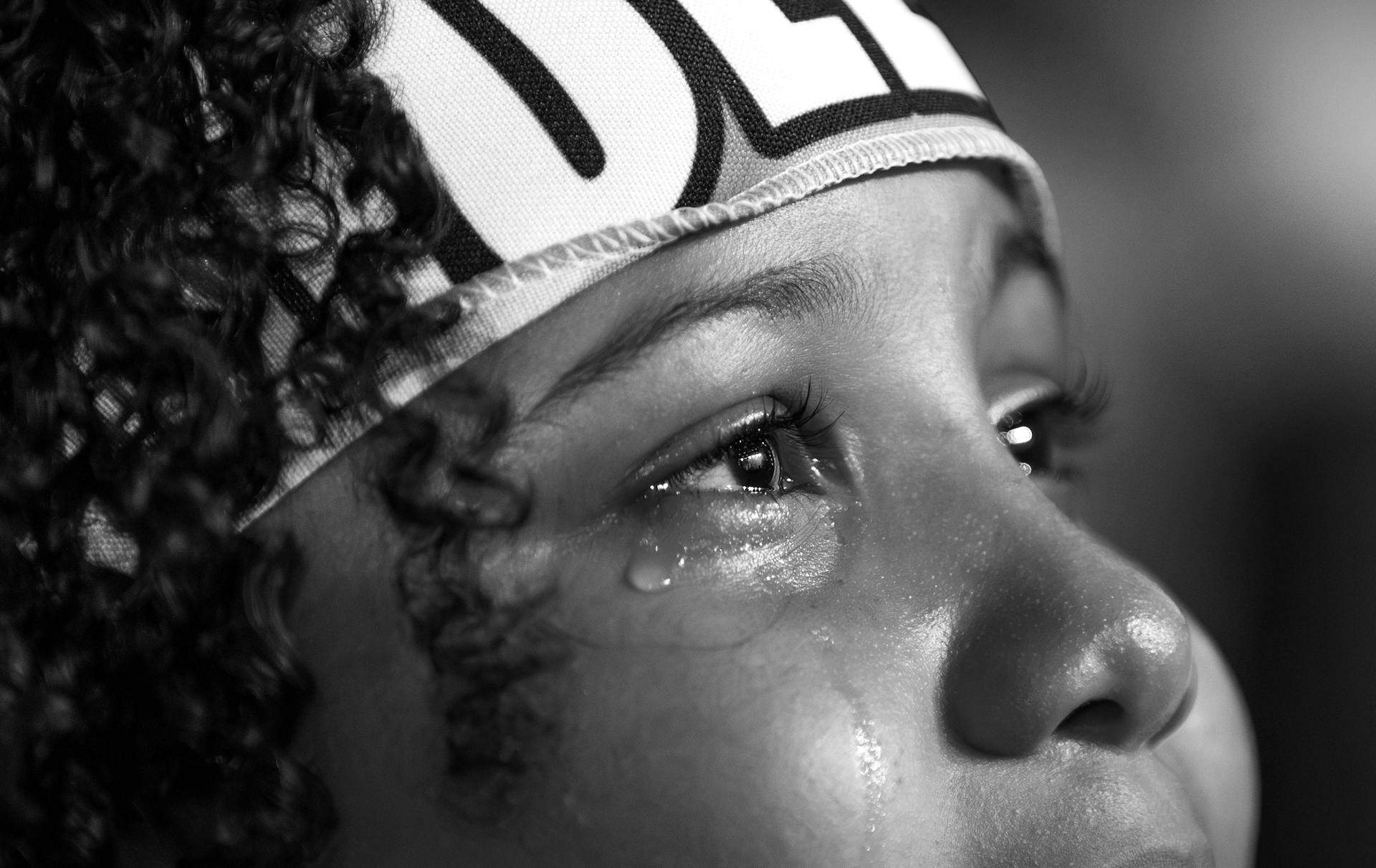 A close-up black and white portrait capturing the emotional expression of a crying child, with tears visible.