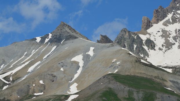 Breathtaking view of rocky mountains with snow patches under a clear blue sky.