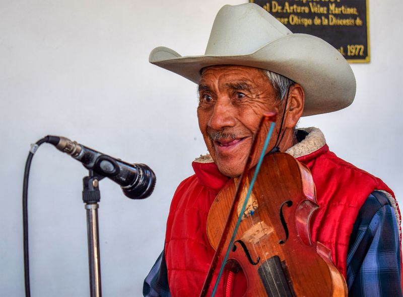 Smiling elderly man in a cowboy hat playing violin in Atlacomulco, Mexico