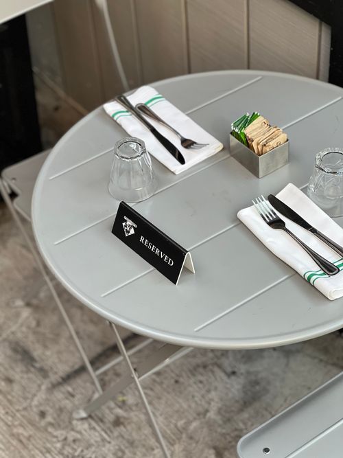 Free A neatly set restaurant table with cutlery, napkins, and a reserved sign, ready for diners. Stock Photo