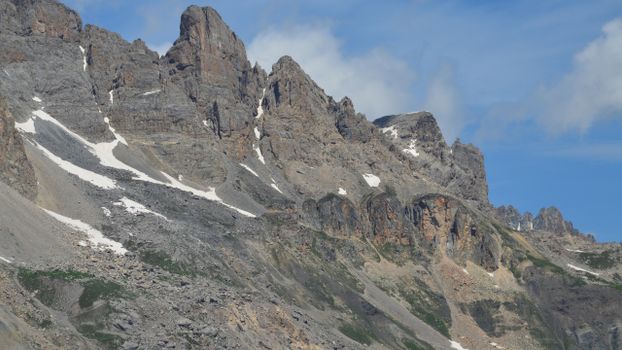 Majestic rocky mountain peaks with patches of snow under a clear blue sky.