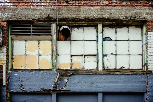 A deteriorating building exterior with damaged windows and peeling paint