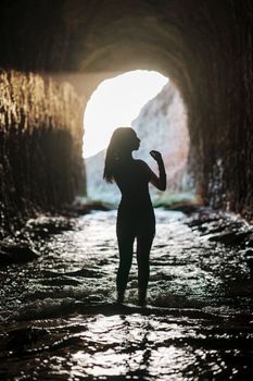 Artistic silhouette of a woman standing in a tunnel with flowing water in Davenport, CA.