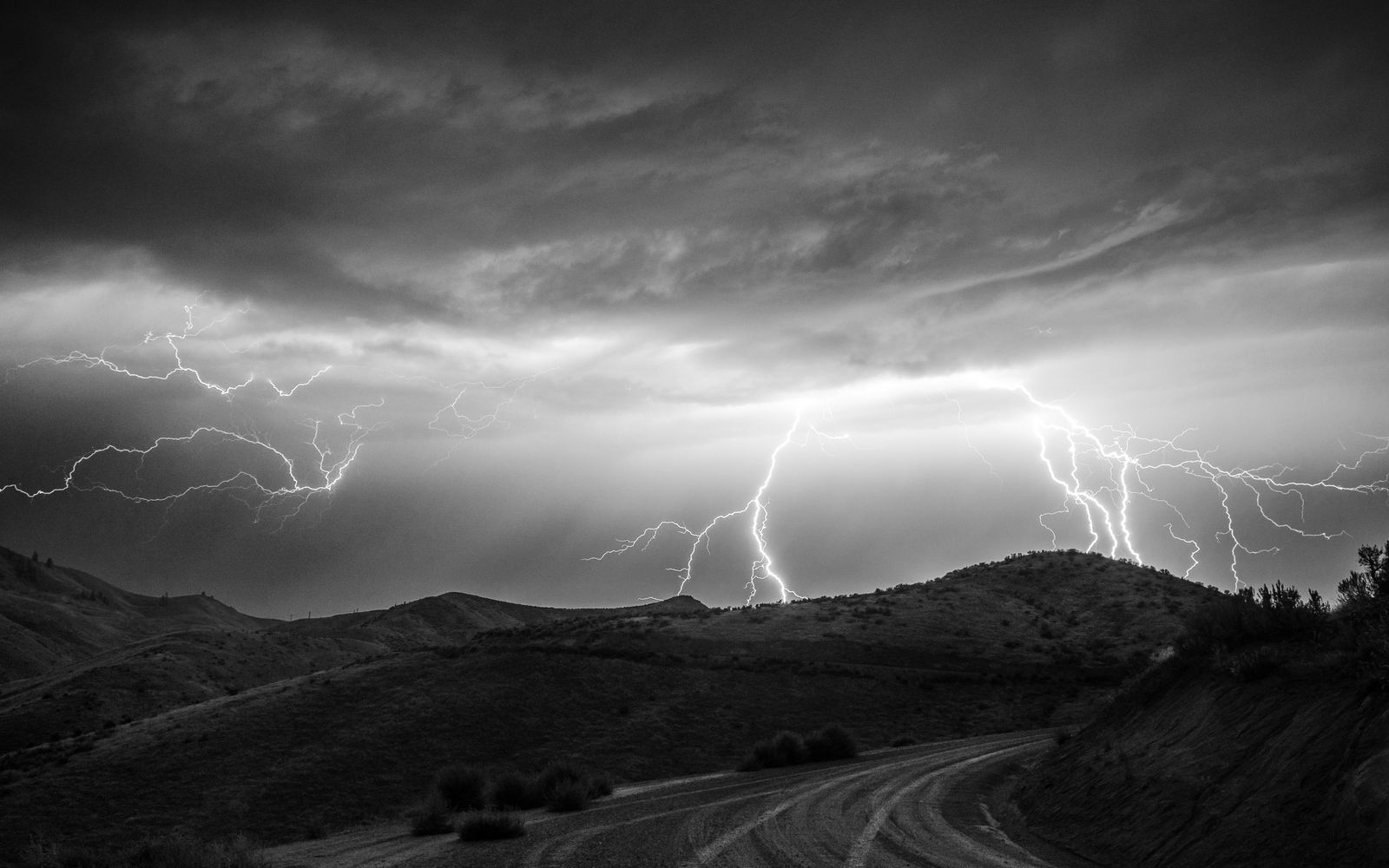 Lightning striking over dry countryside hills during a thunderstorm