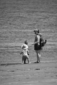 A mother and child exploring the seashore, captured in monochrome for a nostalgic feel.