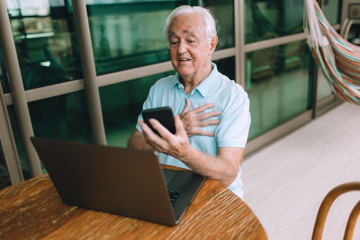 Hombre adulto mayor revisando información en una computadora desde casa