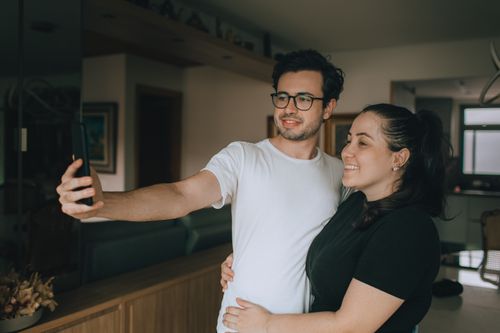 Free A happy couple takes a selfie together in their cozy home setting, capturing a joyful moment. Stock Photo