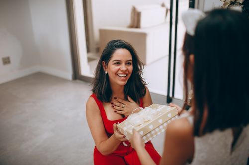 Free A joyful moment as a mother receives a gift from her daughter inside their home. Stock Photo
