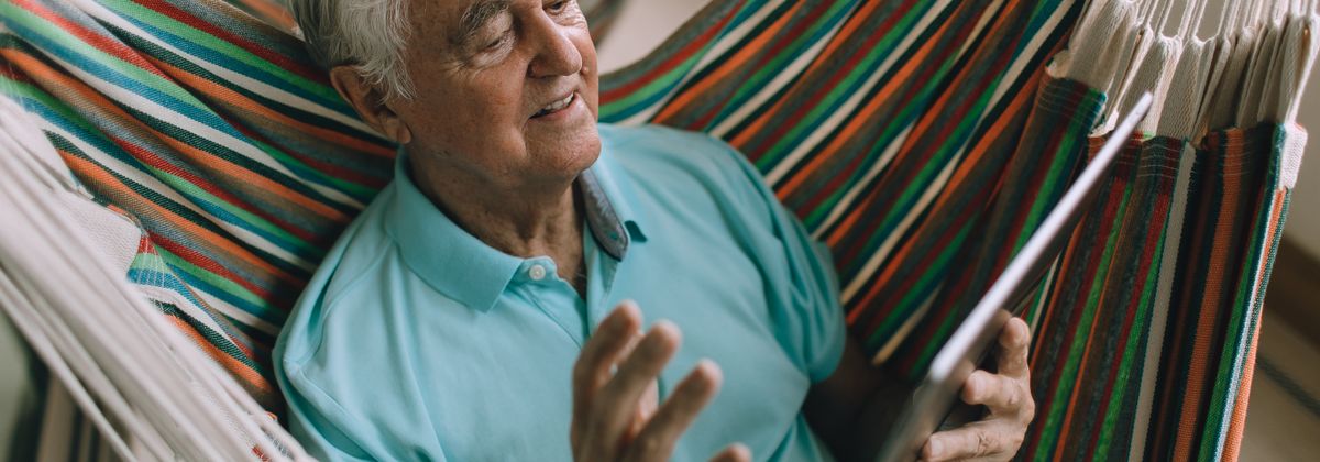 An older man relaxing outdoors with a tablet