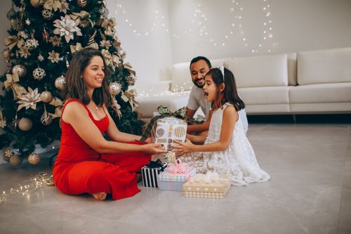 Free Joyful family exchanging gifts near a decorated Christmas tree, capturing festive warmth and togetherness indoors. Stock Photo