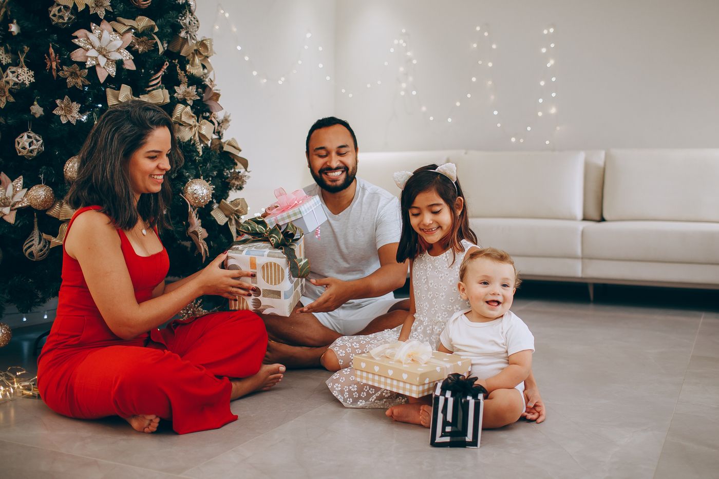 Family opening Christmas presents beside a decorated tree