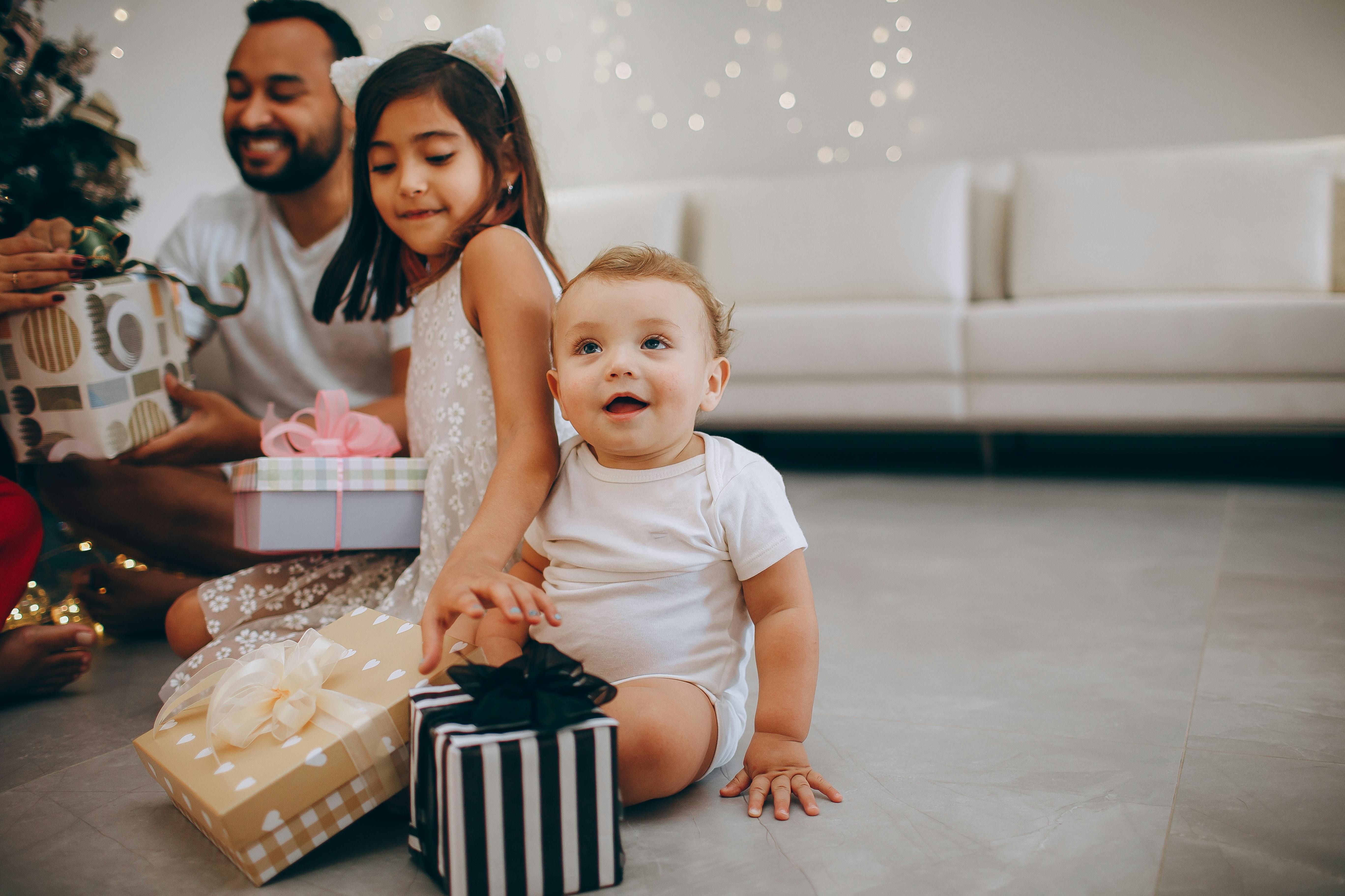 A joyful family scene with children opening Christmas presents indoors.