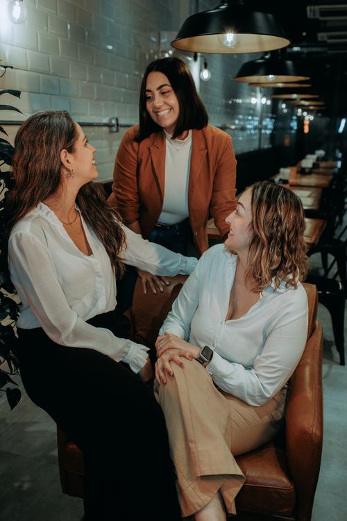 Free A group of three diverse women enjoying a casual business meeting in a cozy cafe setting. Stock Photo