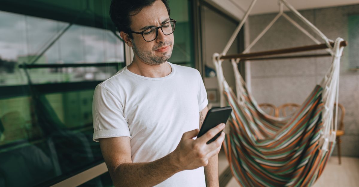 person reading news headlines on smartphone with coffee, thoughtful expression