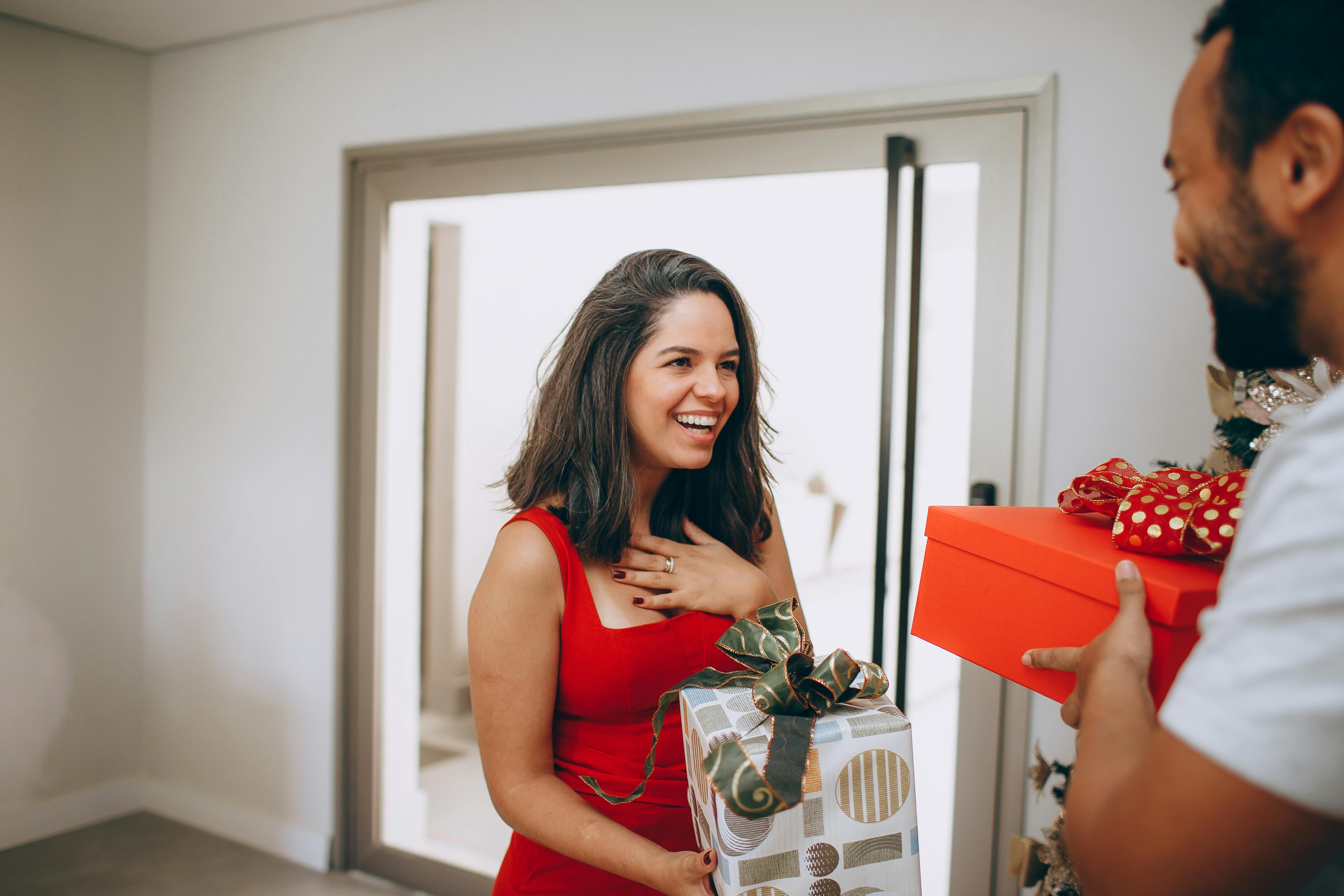 Joyful couple exchanging gifts indoors, capturing the essence of holiday happiness.