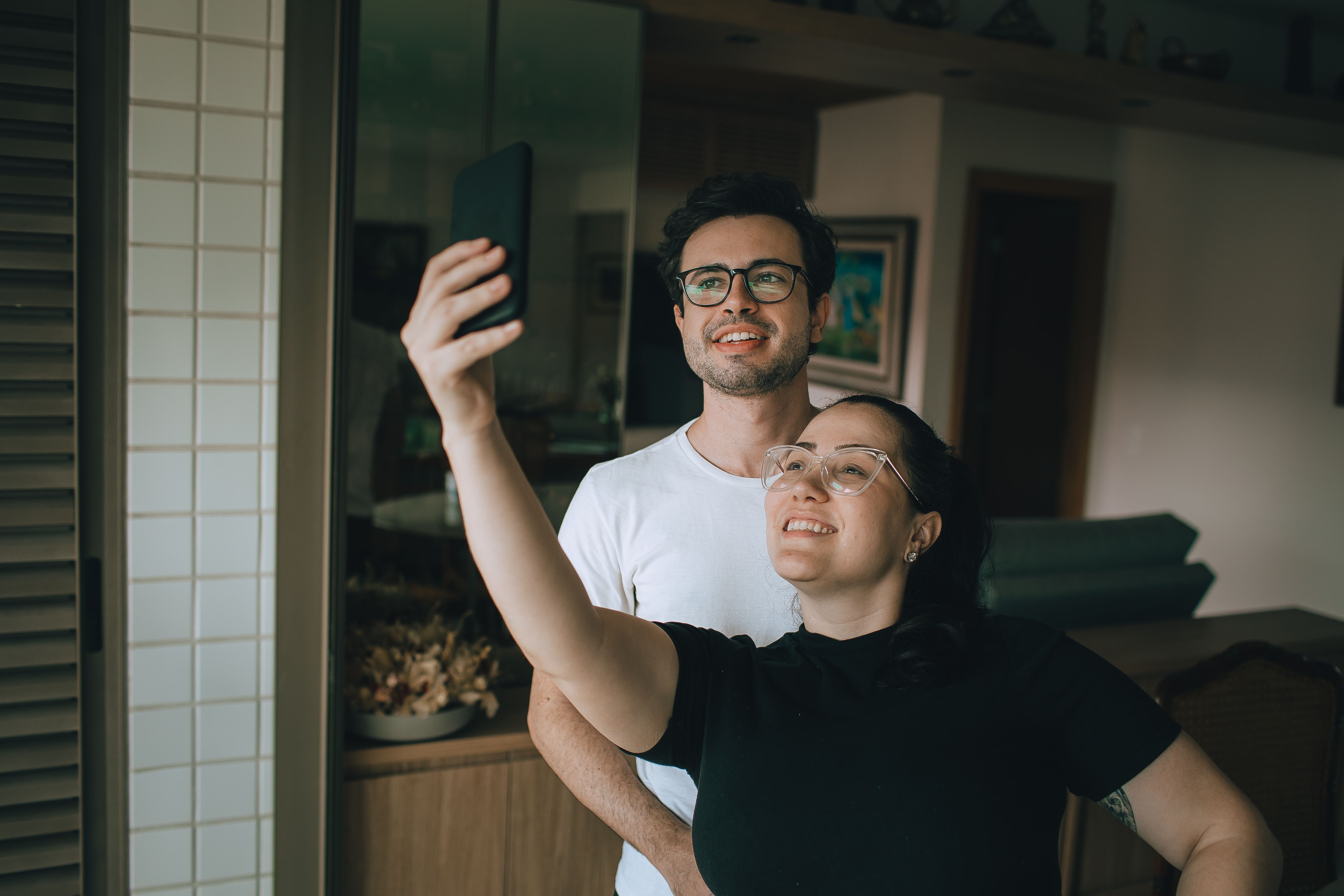 A young couple takes a joyful selfie together in their cozy home environment.