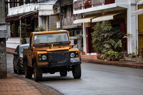 Free A vibrant yellow Land Rover parked on a quiet city street, capturing urban life. Stock Photo