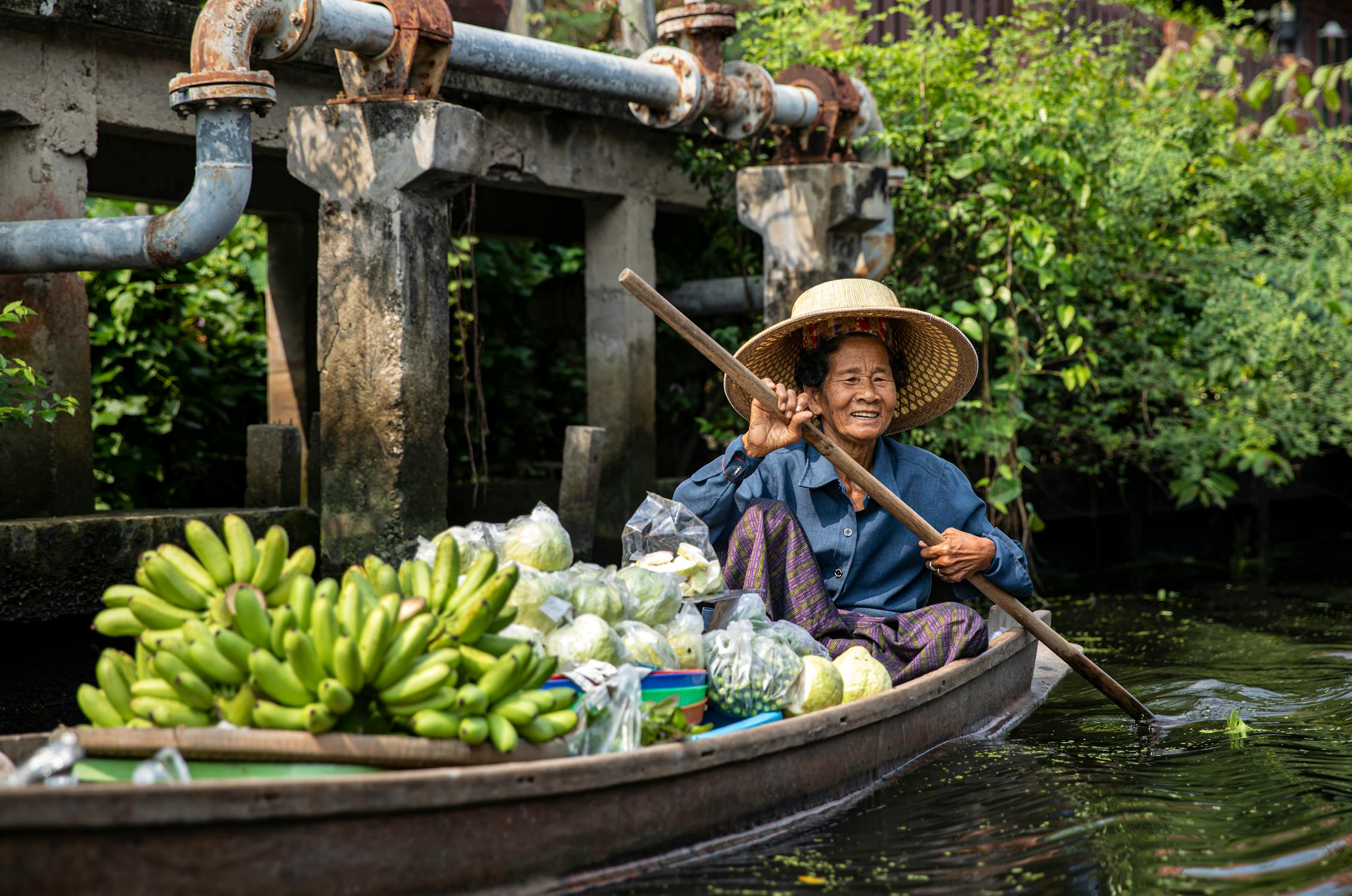 free photo of an elderly woman sitting on a boat with fresh fruit