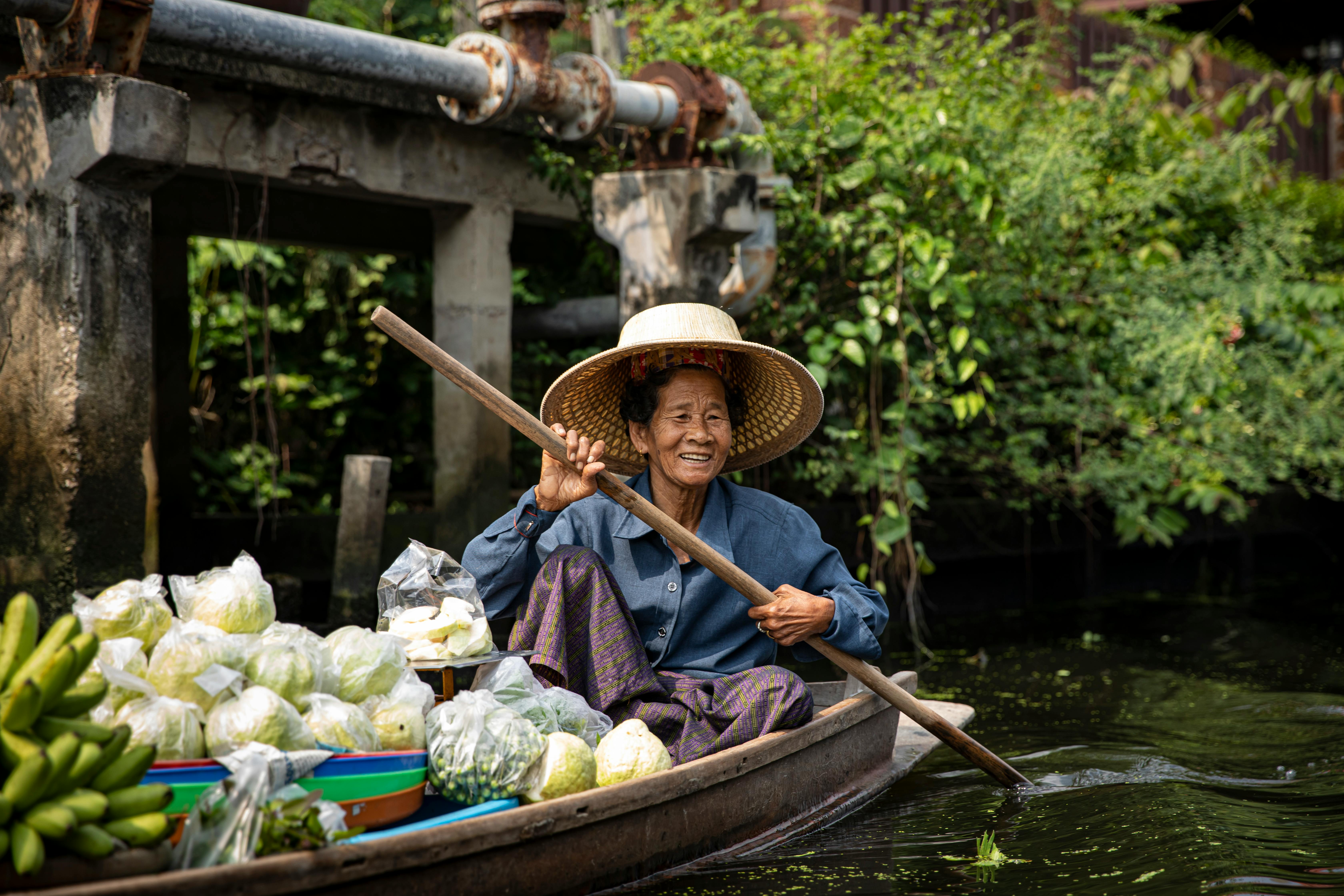 an elderly woman sitting on a boat with fresh fruit