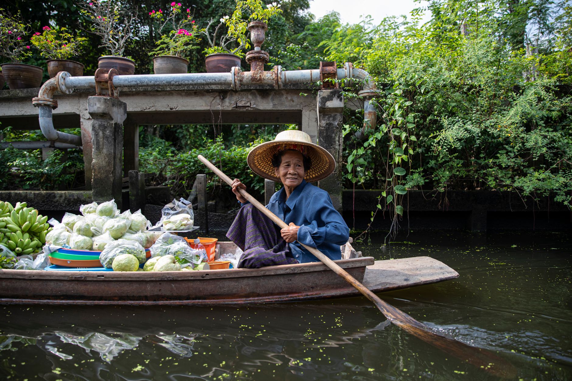 Vendor in a wooden boat cooking noodles at Damnoen Saduak
