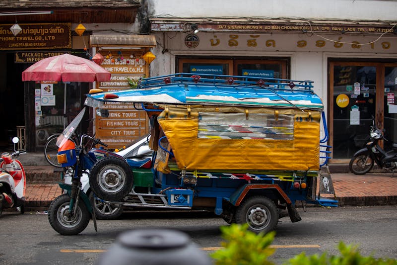 Auto-rickshaw coloré garé sur une rue animée à Paksé, Laos