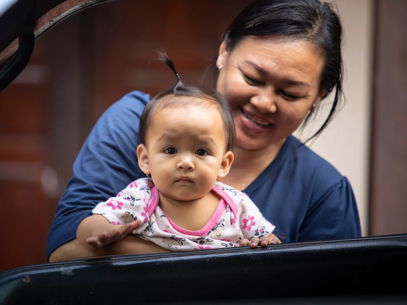 A smiling mother holds her baby close during a quiet moment together