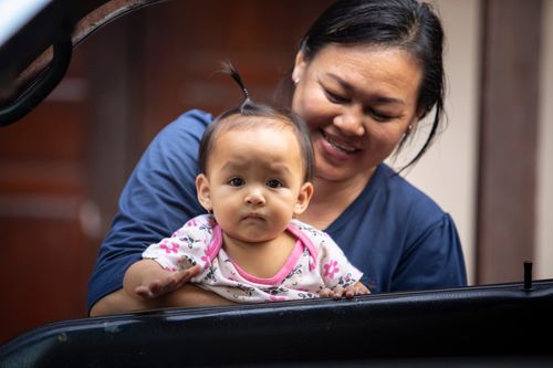 Free A mother joyfully holds her baby, showcasing a moment of family affection and happiness. Stock Photo