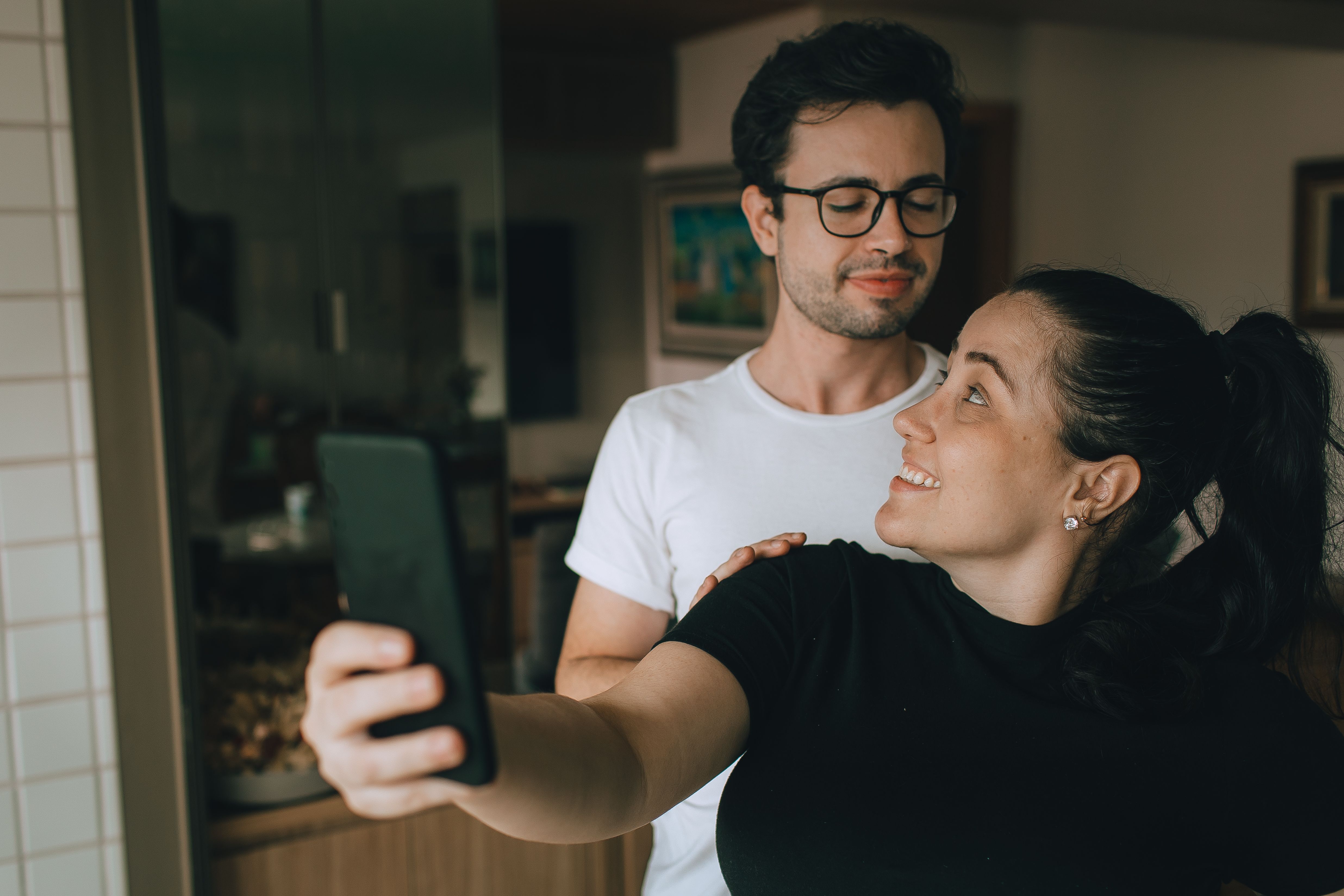 Smiling Couple Taking a Selfie Indoors · Free Stock Photo