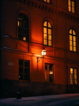 A cozy evening street scene in Stockholm with warm light illuminating historic architecture.