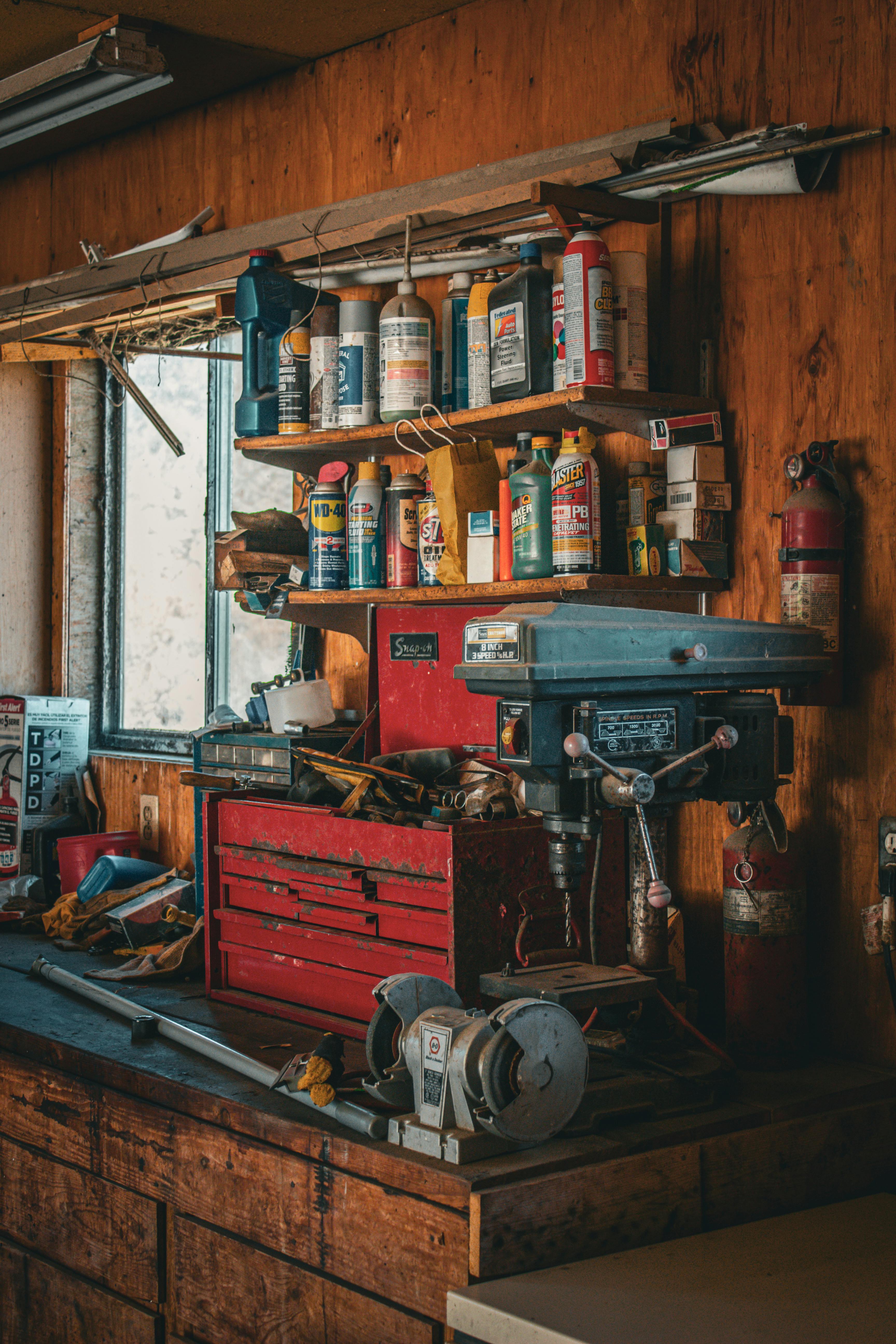 Rustic garage workshop with tools, shelves, and a window for natural lighting.