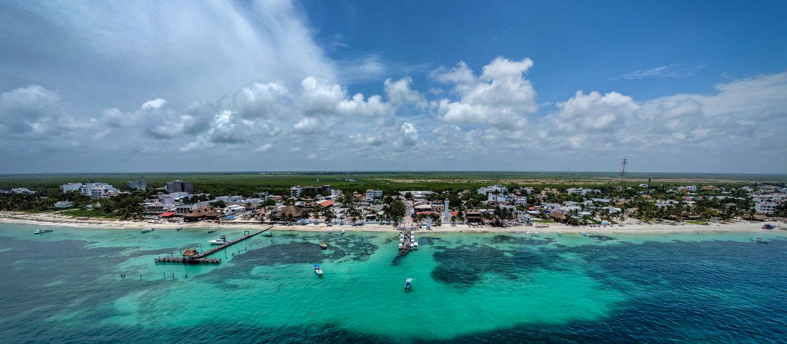 Stunning aerial view of Puerto Morelos, Mexico featuring turquoise waters and coastal town.