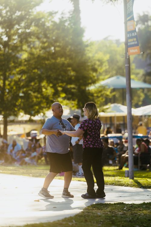 Free A couple is dancing joyfully in a sunny outdoor event, creating a lively summer vibe. Stock Photo