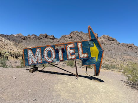 Rustic vintage motel sign in the arid landscape of Nelson Ghost Town, Nevada, under a clear blue sky.