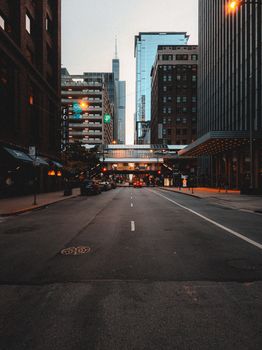 A quiet urban street in Chicago with towering skyscrapers and illuminated street lights.
