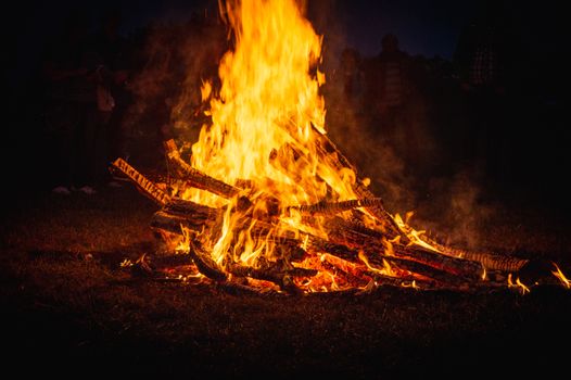 A large bonfire burning brightly at night, illuminating the surroundings.
